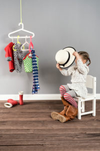 Girl sits on a chair in the wardrobe and wears the shoes of the mother,