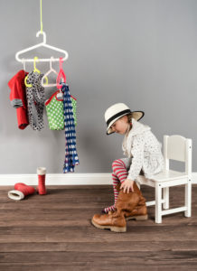 Girl sits on a chair in the wardrobe and wears the shoes of the mother,