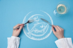 drawing of a fish plate, bird's-eye view, A person holds knife and fork over the plate,