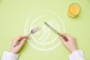 drawing of a vegetable plate, bird's-eye view, A person holds knife and fork over the plate,
