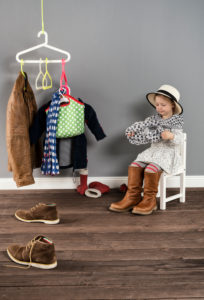 Girl sits on a chair in the wardrobe and wears the shoes of the mother,