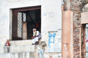 Man sitting in entrance, looking in the distance, graffiti, India, Vrindavan Man sitting in entrance, looking in the distance, graffiti, India, Vrindavan