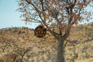 Sign with 'Auf Widersehen' (good bye) in a tree in the Himba country, Namibia Sign with 'Auf Widersehen' (good bye) in a tree in the Himba country, Namibia