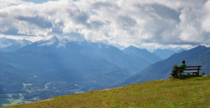 Person on bench enjoys view from Wank towards Berg Daniel (Austria), view over Garmisch-Partenkirchen, Upper Bavaria, Bavaria, southern Germany, Germany Person on bench enjoys view from Wank towards Berg Daniel (Austria), view over Garmisch-Partenkirchen, Upper Bavaria, Bavaria, southern Germany, Germany