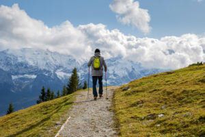 Man hikes on hiking trail at the Wank in Garmisch-Partenkirchen, looking towards the Wetterstein Mountains, blue sky, clouds, Upper Bavaria, Bavaria, southern Germany, Germany Man hikes on hiking trail at the Wank in Garmisch-Partenkirchen, looking towards the Wetterstein Mountains, blue sky, clouds, Upper Bavaria, Bavaria, southern Germany, Germany