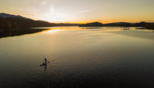 Aerial view of woman with stand up paddle (SUP) on Staffelsee at sunset, Murnau, blue country, Garmisch-Partenkirchen, Upper Bavaria, Bavaria, southern Germany, Germany Aerial view of woman with stand up paddle (SUP) on Staffelsee at sunset, Murnau, blue country, Garmisch-Partenkirchen, Upper Bavaria, Bavaria, southern Germany, Germany