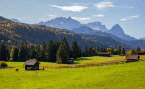 Autumn shot of Holzstadel with horses against Wetterstein Mountains with Alpspitze, Zugspitze and Waxenstones, blue sky, clouds, trees, fence, Garmisch-Partenkirchen, Upper Bavaria, Bavaria, southern Germany, Germany Autumn shot of Holzstadel with horses against Wetterstein Mountains with Alpspitze, Zugspitze and Waxenstones, blue sky, clouds, trees, fence, Garmisch-Partenkirchen, Upper Bavaria, Bavaria, southern Germany, Germany