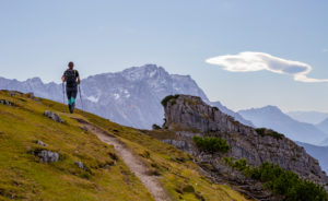 Young woman hiking towards Kramer with a view of the Wetterstein Mountains (with Zugspitze), blue sky, clouds, hiking trail, rock, Garmisch-Partenkirchen, Upper Bavaria, Bavaria, southern Germany, Germany Young woman hiking towards Kramer with a view of the Wetterstein Mountains (with Zugspitze), blue sky, clouds, hiking trail, rock, Garmisch-Partenkirchen, Upper Bavaria, Bavaria, southern Germany, Germany