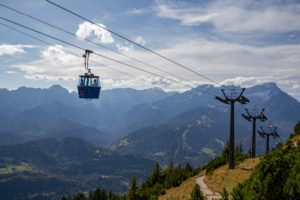 Two people in a historic gondola on the Wank with a view over the Wetterstein Mountains with Alpspitze, Zugspitze and Waxensteine, blue sky, clouds, mountain railway, Garmisch-Partenkirchen, Upper Bavaria, Bavaria, southern Germany, Germany Two people in a historic gondola on the Wank with a view over the Wetterstein Mountains with Alpspitze, Zugspitze and Waxensteine, blue sky, clouds, mountain railway, Garmisch-Partenkirchen, Upper Bavaria, Bavaria, southern Germany, Germany