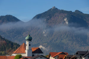 Parish Church of St. Clemens in Eschenlohe in autumn against Ettaler Manndl (Ammergau Alps), mist, blue sky, trees, Garmisch-Partenkirchen, Upper Bavaria, Bavaria, southern Germany, Germany Parish Church of St. Clemens in Eschenlohe in autumn against Ettaler Manndl (Ammergau Alps), mist, blue sky, trees, Garmisch-Partenkirchen, Upper Bavaria, Bavaria, southern Germany, Germany