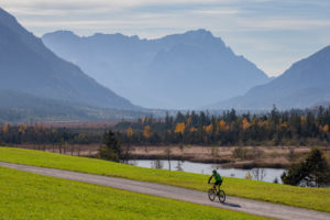Mountain bike riders at the Seven Springs in Eschenlohe in autumn against Wetterstein Mountains with Alpspitze, Waxensteins and Zugspitze, blue sky, clouds, trees, bike path, Garmisch-Partenkirchen, Upper Bavaria, Bavaria, southern Germany, Germany Mountain bike riders at the Seven Springs in Eschenlohe in autumn against Wetterstein Mountains with Alpspitze, Waxensteins and Zugspitze, blue sky, clouds, trees, bike path, Garmisch-Partenkirchen, Upper Bavaria, Bavaria, southern Germany, Germany