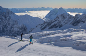 Two young skiers just before setting off on the Zugspitze in winter, looking towards the southeast, high fog, snow, mountain peaks, blue sky, Zugspitze, Grainau, Garmisch-Partenkirchen, Upper Bavaria, Bavaria, southern Germany, Germany Two young skiers just before setting off on the Zugspitze in winter, looking towards the southeast, high fog, snow, mountain peaks, blue sky, Zugspitze, Grainau, Garmisch-Partenkirchen, Upper Bavaria, Bavaria, southern Germany, Germany