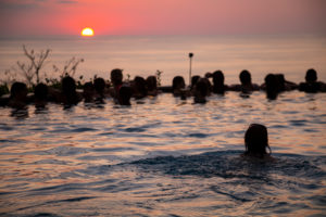 Young woman swims in infinity pool, pool party, sunset, sun, silhouette, ocean, young women, young men, Central America, Costa Rica Young woman swims in infinity pool, pool party, sunset, sun, silhouette, ocean, young women, young men, Central America, Costa Rica