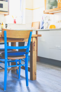 Innenansicht - ein blauer Stuhl, ein Holztisch in einer kleinen Küche in einem Haus. Innenansicht - ein blauer Stuhl, ein Holztisch in einer kleinen Küche in einem Haus.