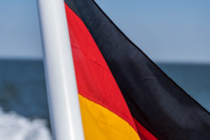 Eine deutsche Fahne, im Wind wehend, auf einem Schiff am Meer. Schwarz, Rot, Gold die Nationalfarben. Symbolbild Eine deutsche Fahne, im Wind wehend, auf einem Schiff am Meer. Schwarz, Rot, Gold die Nationalfarben. Symbolbild