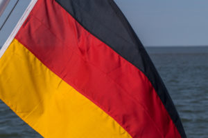 Eine deutsche Fahne, im Wind wehend, auf einem Schiff am Meer. Schwarz, Rot, Gold die Nationalfarben. Symbolbild Eine deutsche Fahne, im Wind wehend, auf einem Schiff am Meer. Schwarz, Rot, Gold die Nationalfarben. Symbolbild
