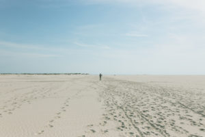 Ein Mann geht durch den Sand. Amrum, eine Insel in der deutschen Nordsee - Sand soweit das Auge reicht. Wittdün Ein Mann geht durch den Sand. Amrum, eine Insel in der deutschen Nordsee - Sand soweit das Auge reicht. Wittdün