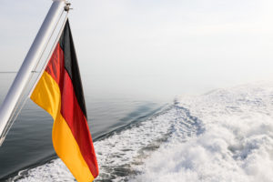 Eine deutsche Fahne, im Wind wehend, auf einem Schiff am Meer. Schwarz, Rot, Gold die Nationalfarben. Symbolbild Eine deutsche Fahne, im Wind wehend, auf einem Schiff am Meer. Schwarz, Rot, Gold die Nationalfarben. Symbolbild