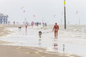 Ein Mann geht nackt mit seinem Hund am Strand spazieren Ein Mann geht nackt mit seinem Hund am Strand spazieren
