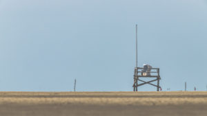 A wooden platform with a beach chair in the middle of the Wadden Sea near St. Peter Ording, recreation on the North Sea A wooden platform with a beach chair in the middle of the Wadden Sea near St. Peter Ording, recreation on the North Sea