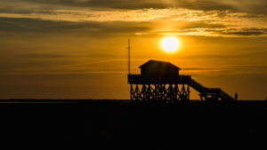 Colorful sunset on the North Sea - in the backlight of the sun a typical stilt house, pile dwellings, pile dwellings that defy the tides. Colorful sunset on the North Sea - in the backlight of the sun a typical stilt house, pile dwellings, pile dwellings that defy the tides.