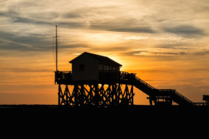 Colorful sunset on the North Sea - in the backlight of the sun a typical stilt house, pile dwellings, pile dwellings that defy the tides. Colorful sunset on the North Sea - in the backlight of the sun a typical stilt house, pile dwellings, pile dwellings that defy the tides.