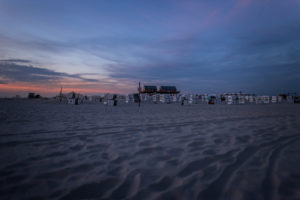 Stilt houses and beach chairs in the last sunlight. Wadden Sea, Much Beach of St. Peter Ording, North Sea at sunset. Stilt houses and beach chairs in the last sunlight. Wadden Sea, Much Beach of St. Peter Ording, North Sea at sunset.