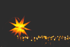 An illuminated poinsettia, in the background a golden chain of lights, copy space