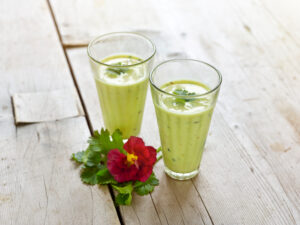 ayurvedic cuisine, two drinking glasses with cucumber parsley buttermilk on light wooden table top