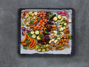 ayurvedic cuisine, baking tray from above with seasonal vegetables from the oven on baking paper