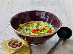 ayurvedic cuisine, vegetable curry in an eggplant colored bowl with a small bowl of raisin ginger chutney and wooden spoon