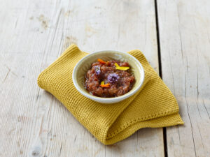 ayurvedic cuisine, a small bowl of raisin ginger chutney wrapped in a mustard yellow cloth on light wooden plate