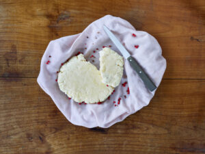 ayurvedic cuisine, paneer or home made fresh cheese in a kitchen towel with knife on a wooden table