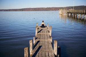 Meditation at the Ammersee, woman sitting on jetty, blue sky Meditation at the Ammersee, woman sitting on jetty, blue sky