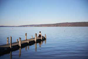Meditation at the Ammersee, woman sitting on jetty, blue sky Meditation at the Ammersee, woman sitting on jetty, blue sky