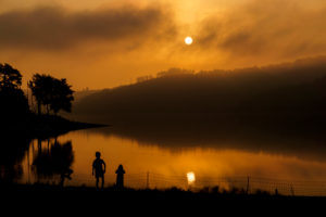 Germany, North Rhine-Westphalia, playing children on the lake in front of the morning sun Germany, North Rhine-Westphalia, playing children on the lake in front of the morning sun
