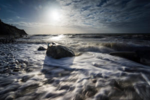 Baltic sea at evening light and long exposure, setting sun lights stones in the sea water Baltic sea at evening light and long exposure, setting sun lights stones in the sea water