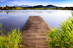 Panorama landscape in Bavaria in Allgäu with bathing jetty, lake and mountains Panorama landscape in Bavaria in Allgäu with bathing jetty, lake and mountains