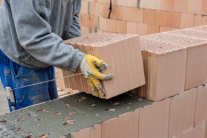Bricklayers build a brick wall on a bare brickwork Bricklayers build a brick wall on a bare brickwork