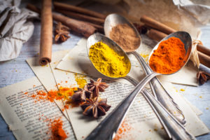 Spices on silver spoons on old book pages Spices on silver spoons on old book pages