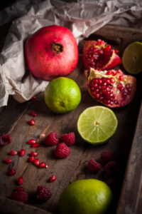 Pomegranate, raspberries and limes in wooden box Pomegranate, raspberries and limes in wooden box