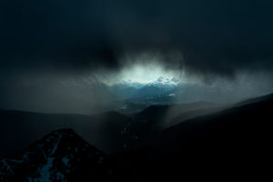 Storm over the Isar valley. Severe weather with the summit cross / mountain peak of the Martinkopf, just below the Herzogstand in the Ester Mountains, the Bavarian Prealps. A dark, heavy storm cloud and rain only allow a small viewing window to Mittenwald, Wallgau and the Wetterstein Mountains. Storm over the Isar valley. Severe weather with the summit cross / mountain peak of the Martinkopf, just below the Herzogstand in the Ester Mountains, the Bavarian Prealps. A dark, heavy storm cloud and rain only allow a small viewing window to Mittenwald, Wallgau and the Wetterstein Mountains.