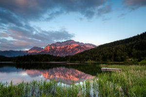 The Lautersee near Mittenwald reflects the alpine glow of the Karwendel, with reeds and a footbridge in the foreground. The Lautersee near Mittenwald reflects the alpine glow of the Karwendel, with reeds and a footbridge in the foreground.