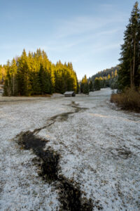 A small hay barn on a bog meadow in hoar frost. A small stream leads to the hut in the clearing