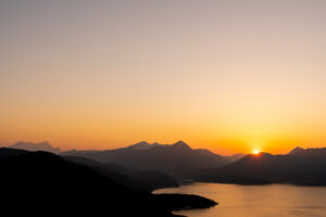 Cloudless sunset with orange evening sky over the Walchensee, in the background the Simetsberg, the Estergebirge and far left the Zugspitze.