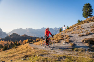 A man rides an ebike MTB on the tracks in the San Nicolò valley, Fassa valley, Trentino, Dolomites, Italy