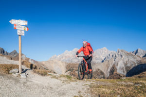 A man with ebike MTB on the tracks in the San Nicolò valley with Marmolada on the background, Trentino, Dolomitenes, Italy