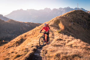 A man rides an ebike MTB on the tracks in the San Nicolò valley, Fassa valley, Trentino, Dolomites, Italy A man rides an ebike MTB on the tracks in the San Nicolò valley, Fassa valley, Trentino, Dolomites, Italy