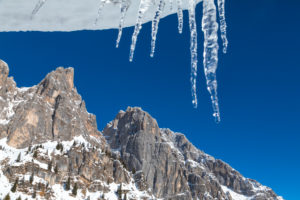 hanging icicles towards a blue sky, in the background la croda granda, group of pale di san martino, dolomites, belluno, veneto, italy