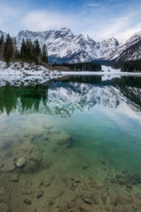 The upper lake of Fusine with mount Mangart on the background in winter. Fusine Lakes Natural Park, Fusine di Valromana, Tarvisio, Udine province, Friuli Venezia Giulia, Italy